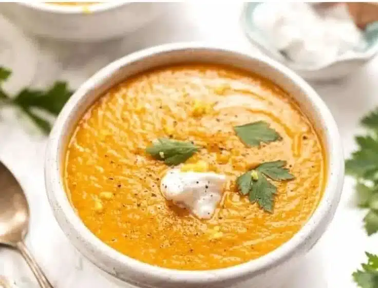Bowl of delicious anti-inflammatory carrot soup garnished with fresh herbs.