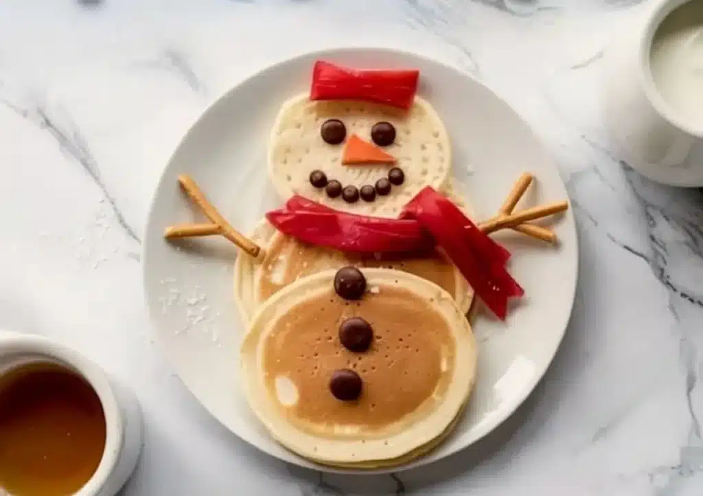 Delicious and festive snowman pancakes stacked with syrup and toppings.