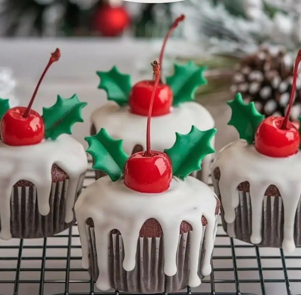 Festive Christmas pudding cupcakes topped with a smooth vanilla glaze, perfect for holiday desserts.