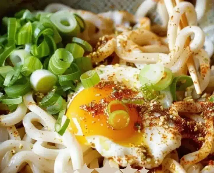 Bowl of Kimchi Butter Udon topped with a soft boiled egg, garnished with green onions.