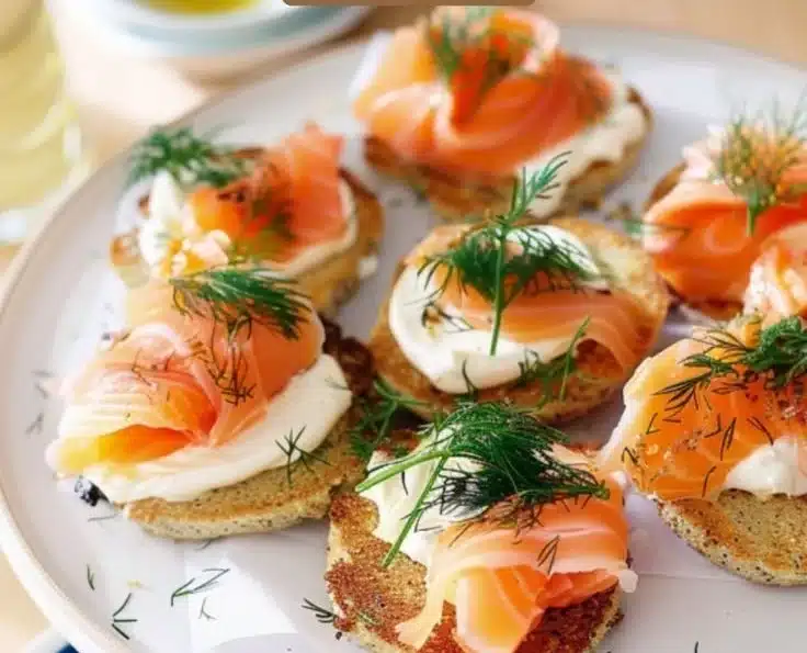 Smoked Salmon & Dill Blini Cake 5 Smoked salmon and dill blini cake garnished with fresh herbs.