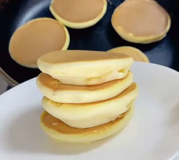 Fluffy soufflé pancakes prepared in a pan, showcasing their light and airy texture.