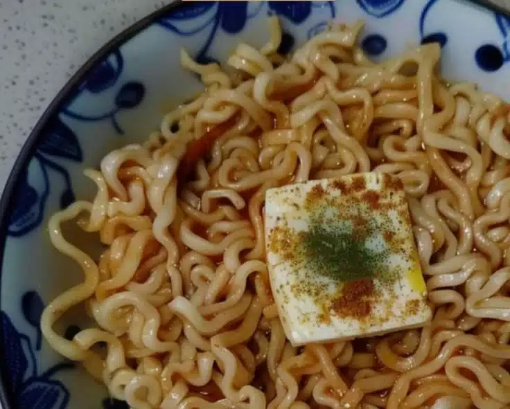 Bowl of Garlic Butter Ramen topped with green onions and garlic cloves