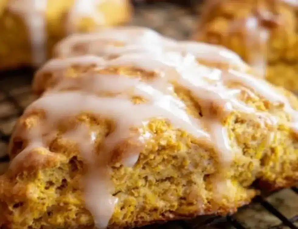 Freshly baked pumpkin scones drizzled with maple glaze on a plate