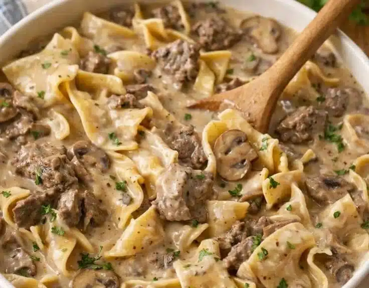 Delicious slow cooker beef stroganoff served with noodles and garnished with parsley